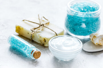 Fototapeta na wymiar blue bath salt, body cream and shells for spa on white table background