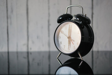 Alarm clock on glass table, wake up in the morning, vintage. Blur wall background