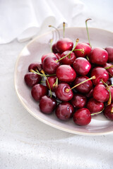 Fresh red ripe juicy cherries on a plate close up in a high key