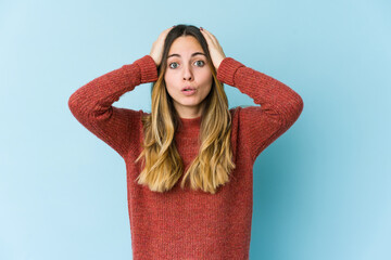 Young caucasian woman isolated on blue background being shocked, she has remembered important meeting.