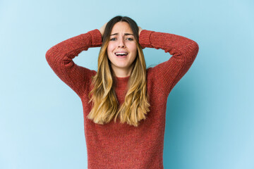 Young caucasian woman isolated on blue background screaming with rage.