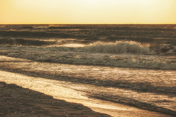 Sea waves roll along the sandy coast of the Black Sea in the evening