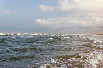 On a cloudy day, sea waves roll over the sandy coast of the Adriatic Sea. Rimini. Italy