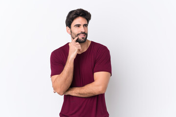 Young handsome man with beard over isolated white background thinking an idea while looking up
