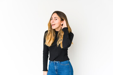 Young caucasian woman isolated on white background trying to listening a gossip.