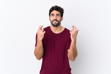 Fototapeta premium Young handsome man with beard over isolated white background with fingers crossing and wishing the best