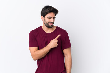 Young handsome man with beard over isolated white background pointing to the side to present a product