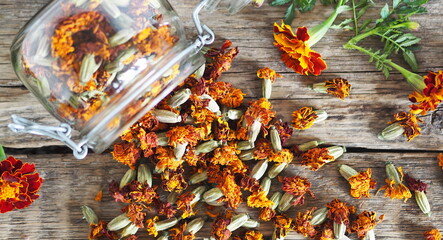 Folk medicine. Dried red flowers of marigold-marigolds on a wooden background in a glass jar for storage.The benefits of medicinal herbs.