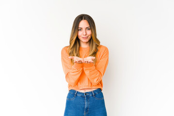 Young caucasian woman isolated on white background holding something with palms, offering to camera.