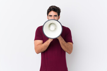 Young handsome man with beard over isolated white background shouting through a megaphone