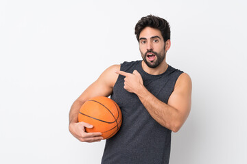 Obraz premium Basketball player man with beard over isolated white background surprised and pointing side