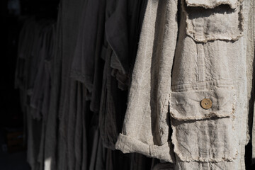 Clothes made from natural raw linen on hangers in a store close-up