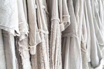 Clothes made from natural raw linen on hangers in a store close-up