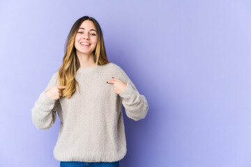 Young caucasian woman isolated on purple background surprised pointing with finger, smiling broadly.