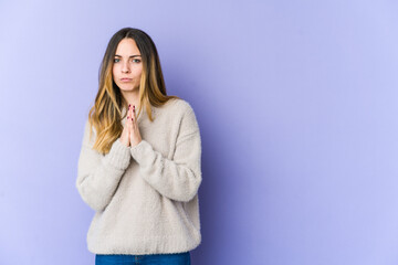 Young caucasian woman isolated on purple background praying, showing devotion, religious person...