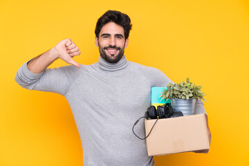 Young handsome man with beard making a move while picking up a box full of things over isolated...