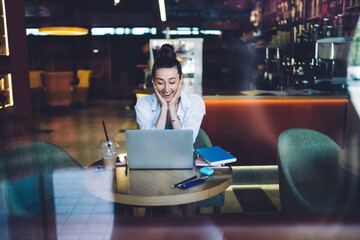 Obraz na płótnie Canvas Positive businesswoman using laptop in cafeteria