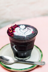 Glasse of Super Latte such as Black Latte from activated charcoal, date syrup and nut milk, healthy drink with latte art