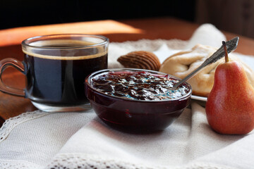 Sweet Breakfast, coffee, bun, jam, candy and pear on a napking