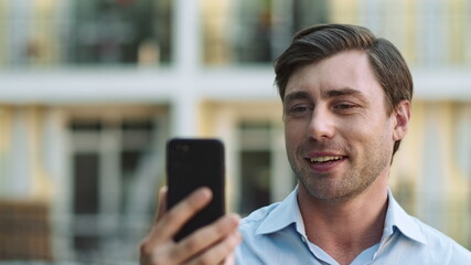 Obraz na płótnie Canvas Portrait man using phone for video chat. Businessman making video call outside
