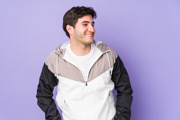 Young man isolated on purple background confident keeping hands on hips.