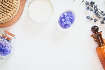 Background for relax. Copy space. White candle, flowers of lavender, decorative bottles, brush for massage, sea salts, lemon on the white background.