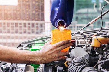 Auto mechanic is filling up the car's engine oil inside the auto repair center, the auto industry...