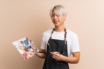 Young asian man over isolated background holding a palette