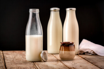 Bottles of fresh milk with small jug on rustic table