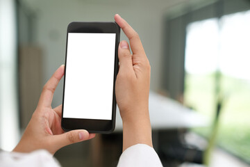 Cropped shot of hands holding mock up smartphone with blank screen in office.