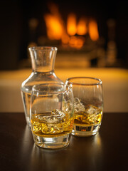 Fototapeta na wymiar scotch whisky glassees with decanter and fire in background