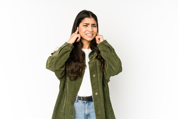 Young indian woman isolated on purple background covering ears with hands.