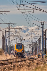 High speed train passing beneath catenary cables with heat haze