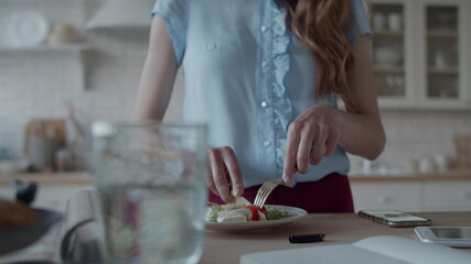 Attractive woman having quick lunch in home kitchen. Lady eating salad.