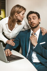 Female Head of office embraced the male employee working at his workplace. Seducing a subordinate in the office. High quality photo.