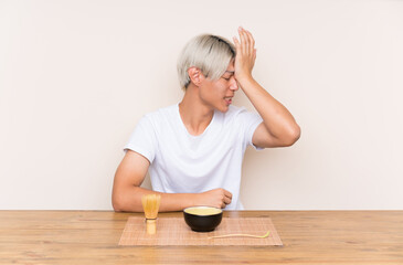 Young asian man with matcha tea in a table having doubts with confuse face expression