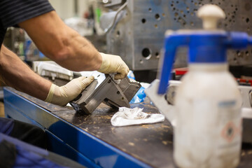 Technician cleaning a parts of mold for molding plastic in a plastic factory, industry concept