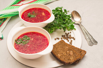 Borsch is a traditional Ukrainian soup. Vegetable soup with sour cream in a white ceramic cup on a white metal tray.
