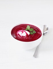 Beet soup-puree with sour cream and parsley in a bowl on a light background