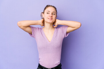 Young caucasian woman on purple background feeling confident, with hands behind the head.