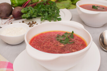 Borsch is a traditional Ukrainian soup. Two white ceramic cups with vegetable soup.