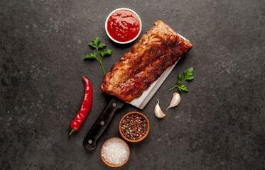 grilled pork ribs on a meat knife on a stone background