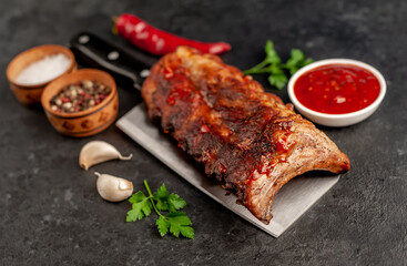 grilled pork ribs on a meat knife on a stone background