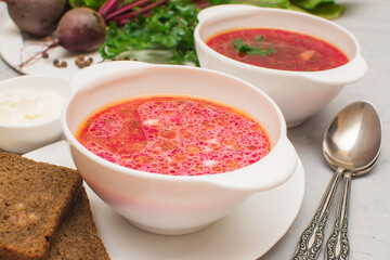 Borsch is a traditional Ukrainian soup. Two white ceramic cups with vegetable soup.