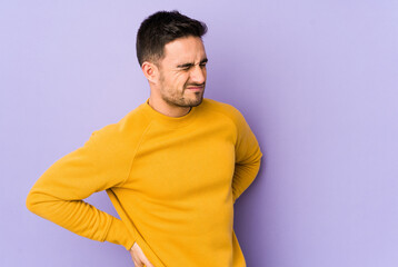 Young caucasian man isolated on purple background suffering a back pain.