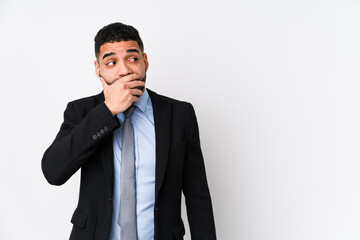 Young latin business woman against a white background isolated thoughtful looking to a copy space covering mouth with hand.