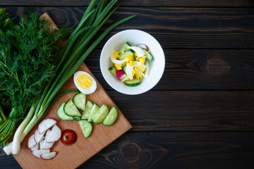 Fresh vegetables on a cutting board with herbs for salad on a dark background. Diet Food Top View