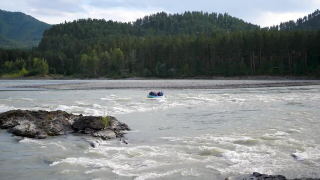 Group of people sails in the inflatable boat on the mountain river. Rafting sports