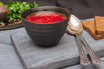 Borsch is a traditional Ukrainian soup. Vegetable soup with sour cream in a ceramic cup on an old wooden surface.