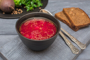 Borsch is a traditional Ukrainian soup. Vegetable soup with sour cream in a ceramic cup on an old wooden surface.